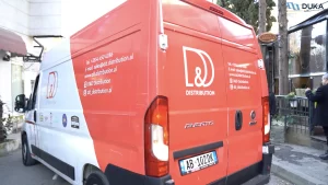 A red and white 'D&D Distribution' delivery van parked on the street, with company contact information and logos of associated brands displayed on the vehicle.