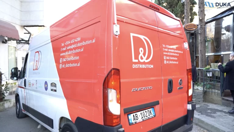 A red and white 'D&D Distribution' delivery van parked on the street, with company contact information and logos of associated brands displayed on the vehicle.